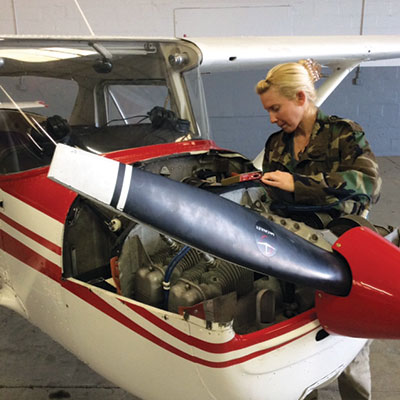 A man in camouflage sitting inside of an airplane.