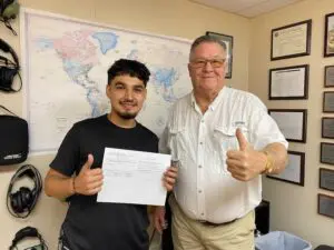Two men giving thumbs up in office.