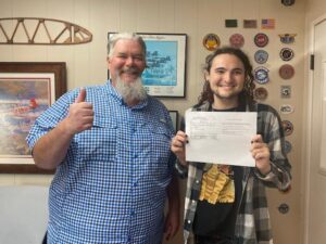 Two men proudly holding paperwork with smiles.