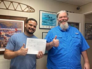 Two men smiling and giving thumbs up.