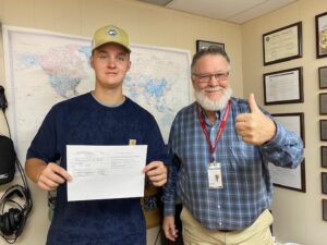 Two men proudly displaying a completed form.