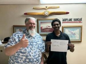 Two men smiling, one holding a document.