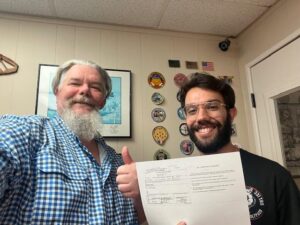 Two men smiling with a document in office.
