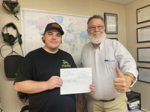 Two men proudly displaying a signed document.