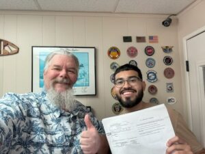 Two men smiling and holding a document.