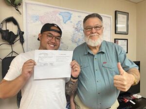 Two men proudly holding a document together.