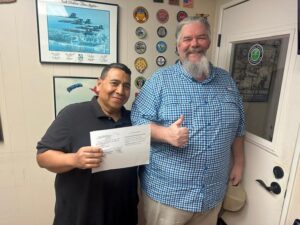Two men joyfully displaying a document together.
