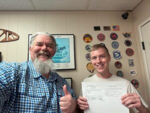 Two men smiling with a document in hand.