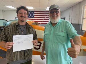 Two men proudly displaying a document together.